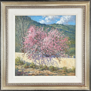 Spring landscape painting titled “Plum Tree in Bloom” by Charles M. Pruitt (American, b. 1941), oil on panel, showing a pink-blossomed tree behind a low stucco wall with mountains in the background.